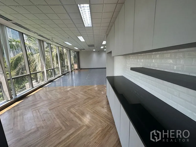 Office Space for rent - Pantry wall with white cabinets, black countertop and long windowed workspace with mixed flooring.