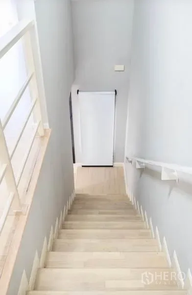 Townhouse for rent or sale in Watthana, Bangkok - Bright stairwell with light wood steps and white handrail inside the townhouse.