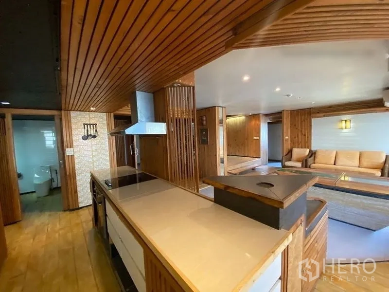Condominium for rent or sale in Suan Luang, Bangkok - Open-plan kitchen flowing to the living area with sofa, long counter and range hood.