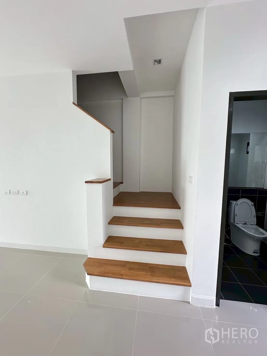 สำนักงานที่บ้าน for rent in Lat Phrao, Bangkok - โถงทางเข้าพื้นกระเบื้องเงา นำไปสู่บันไดไม้ ข้างประตูห้องน้ำ.