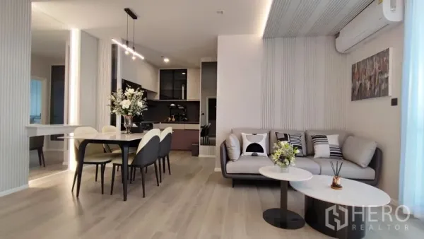 Condominium for rent in Bang Kho Laem, Bangkok - Spacious lounge and dining space beside a sleek kitchenette and pale wood flooring.