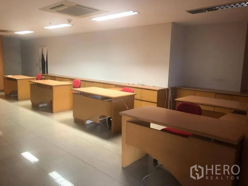 办公空间 出租在Sathon, Bangkok - 一排木质办公桌配红色椅子，明亮吊顶灯与瓷砖地面。