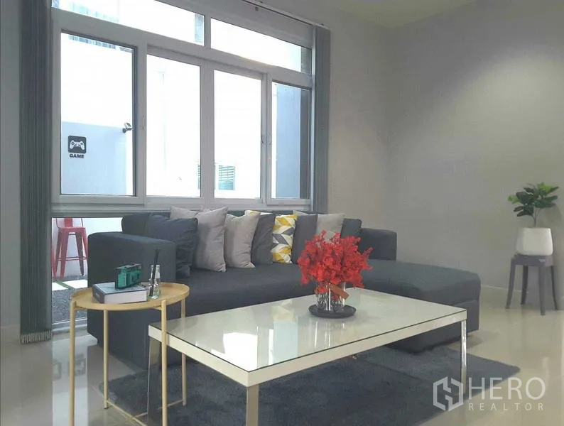 บ้าน ให้เช่าในLam Luk Ka, Pathum Thani - มุมนั่งเล่นอบอุ่น โซฟาตัวแอลและโต๊ะกลางกระจก ใกล้หน้าต่าง