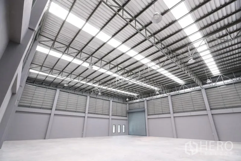 Factory for rent or sale in Bang Bo, Samut Prakan - Warehouse corner with a roller shutter door and tall walls suitable for racking.