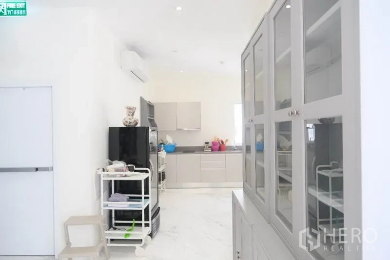 Home Office for rent or sale in Prawet, Bangkok - Pantry corridor with glass-front cabinets leading to a bright kitchen.
