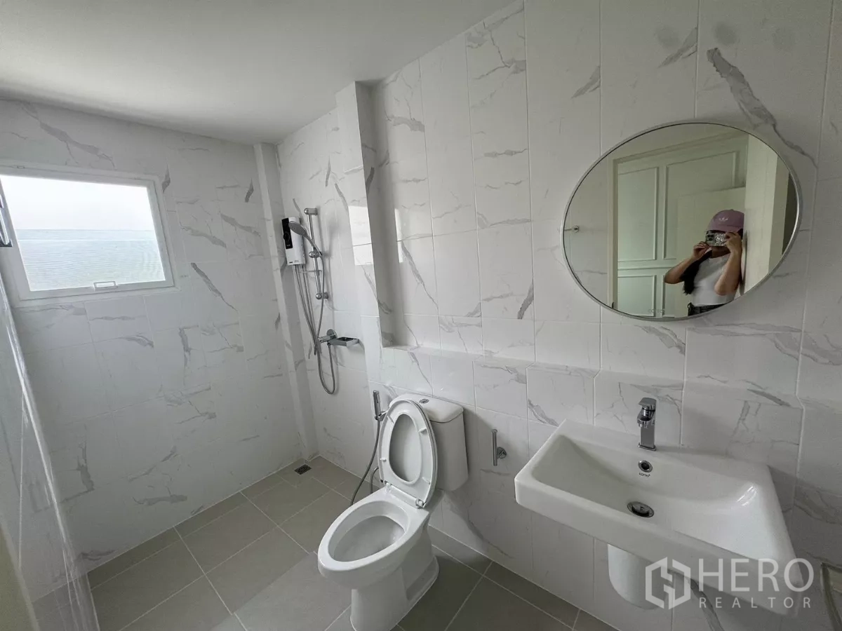 Detached House for rent or sale in Bang Bo, Samut Prakan - Bright bathroom with marble-style tiles, shower, and round mirror.