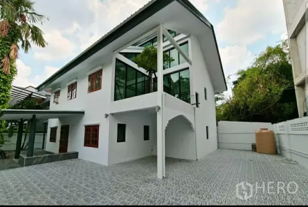 带办公室的家 出租在Lat Phrao, Bangkok - 外立面斜角视图，玻璃转角空间、宽阔铺装车道与成树景观。