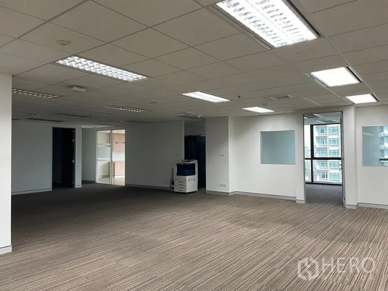 Office Space for rent - Spacious open office with drop ceiling lights, a copier station and balcony-style window access.