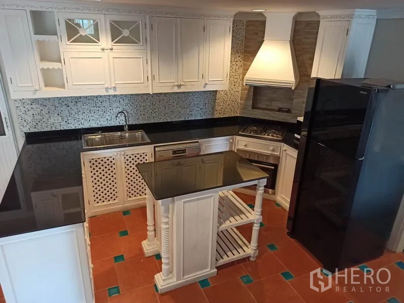 独立式住宅 出租在Mueang Samut Prakan, Samut Prakan - 俯视厨房，中岛、抽油烟机、黑色台面与瓷砖地面一览。