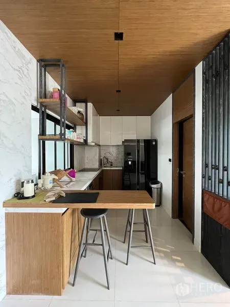 联排别墅 出租在Saphan Sung, Bangkok - 早餐吧台与紧凑厨房，木质橱柜、吊灯与大冰箱。