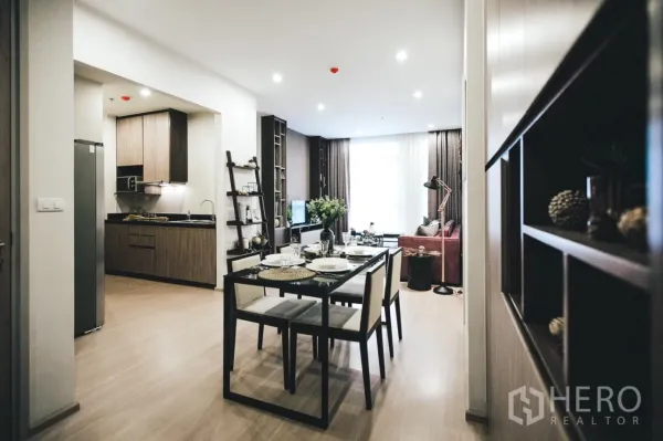 Condominium for rent in Huai Khwang, Bangkok - Open-plan dining area beside the kitchen and lounge, with recessed lighting and wood floors.