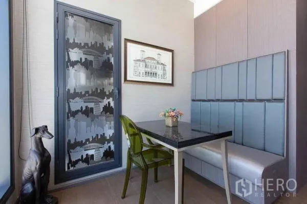 Condominium for sale in Bang Rak, Bangkok - Compact dining nook with built-in banquette seating, black stone table, frosted cityscape door, and decorative accents.