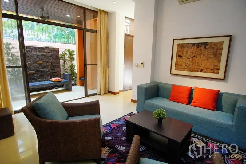 Townhouse for rent in Watthana, Bangkok - Living room opens to a patio with stacked-stone feature wall and daybed.