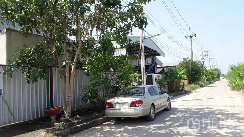 货栈 出售在Pathum Thani - 仓库外安静的通行道路，两侧有树及电线杆，并可路边停车。