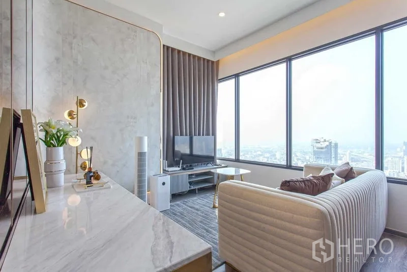 Condominium for rent in Watthana, Bangkok - Bright living room with marble console, gold accents and floor-to-ceiling windows overlooking the Bangkok skyline.