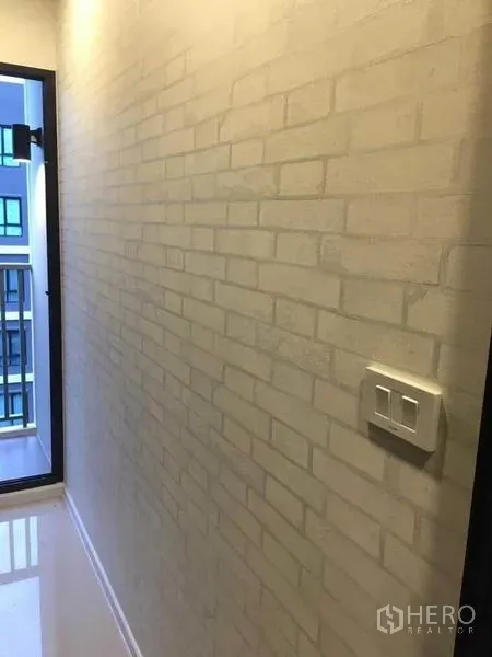 คอนโด ขายในBang Na, Bangkok - โถงทางเดินสว่าง ผนังลายอิฐสีขาวเชื่อมต่อสู่ระเบียงขนาดเล็ก มองเห็นอาคารใกล้เคียง