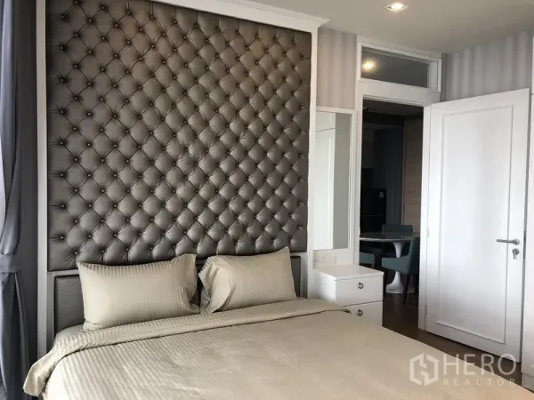 Condominium for rent in Khlong Toei, Bangkok - Master bedroom featuring tufted headboard, bedside vanity, and soft lighting.