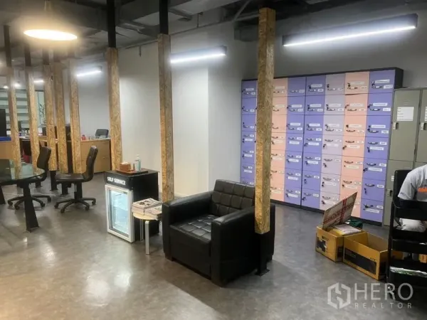 Office Space for rent - Reception lounge with a black armchair, mini fridge, and a wall of colorful lockers inside the office.