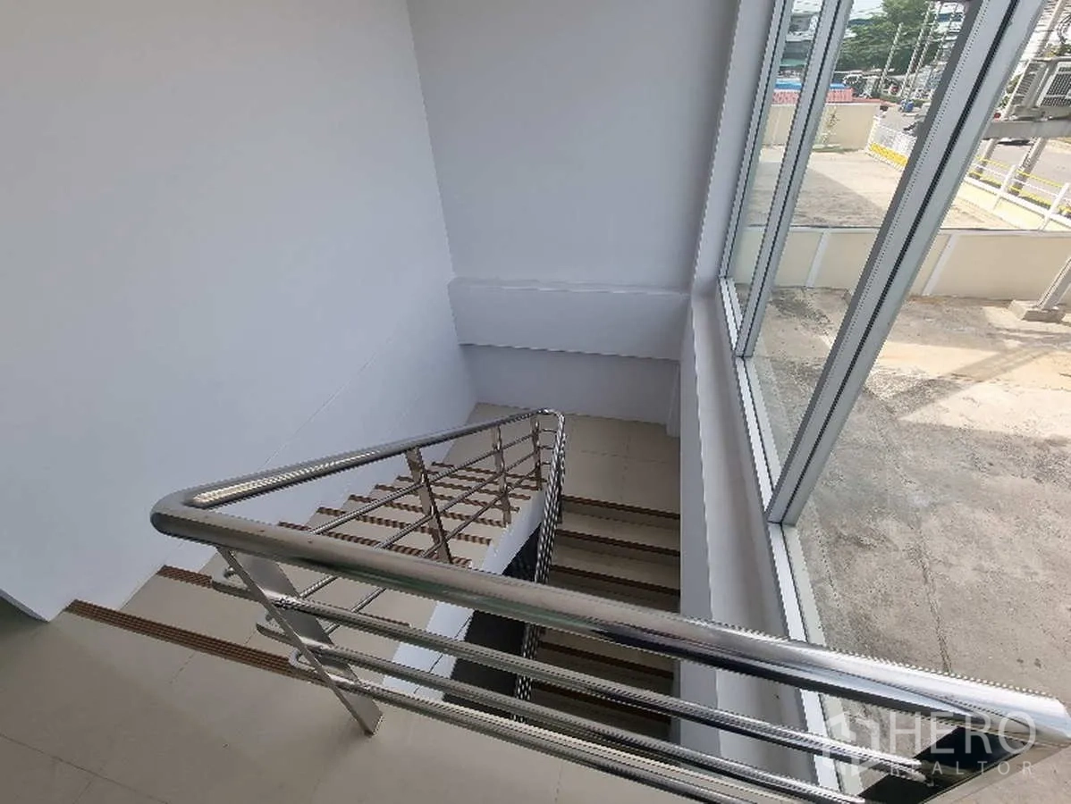 Factory for rent in Samut Prakan - Staircase with stainless-steel railing beside large glazing.