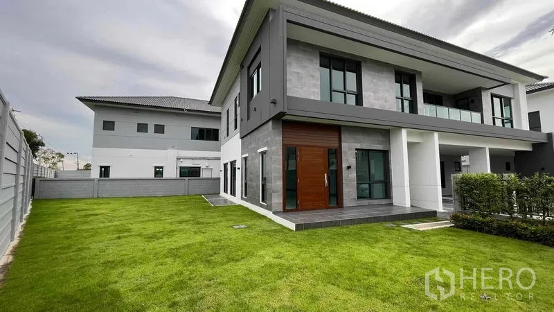 Detached House for sale in Bang Phli, Samut Prakan - Large side and rear lawn wrapping the contemporary two-storey house with privacy wall.