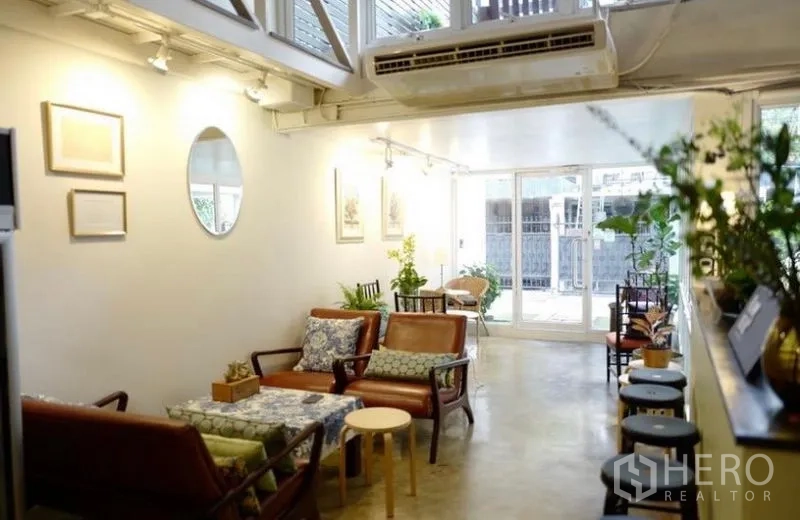 ทาวน์เฮาส์ ให้เช่าในKhlong Toei, Bangkok - ห้องนั่งเล่นแบบโอเพ่น โซฟาหนัง หน้าต่างบานใหญ่ และมุมต้นไม้