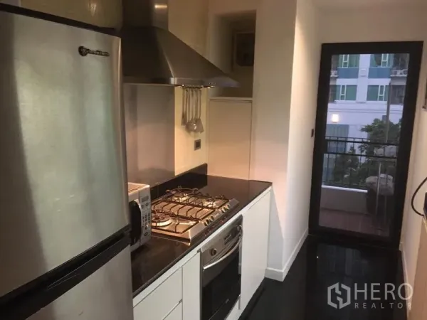 คอนโด ให้เช่า - ครัวแบบแกลลีย์ ตู้เย็นสแตนเลส เตาแก๊ส เตาอบ เครื่องดูดควัน และประตูออกระเบียงเล็ก