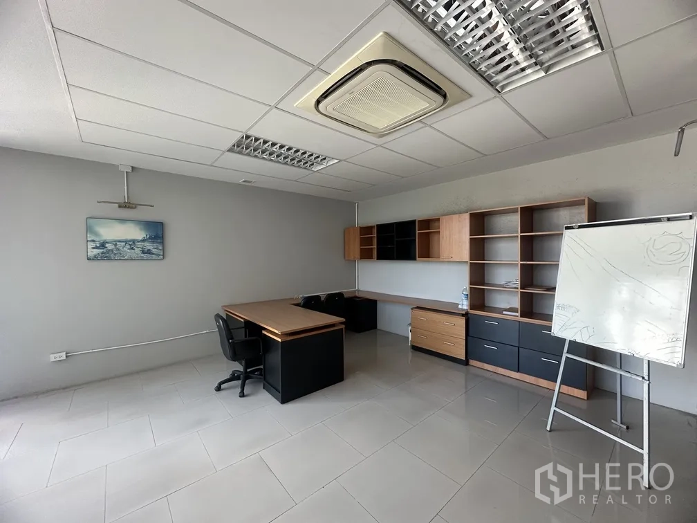 Factory for rent in Lam Luk Ka, Pathum Thani - Spacious office with built-in wall cabinets, desks and a flip chart.