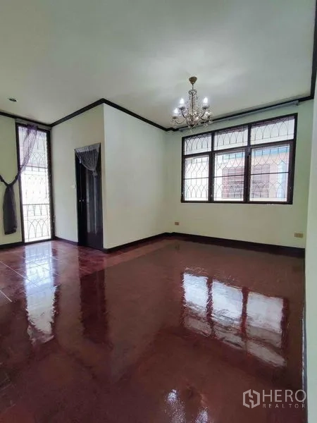 Detached House for rent in Khlong Toei, Bangkok - Bedroom with chandelier, glossy wooden floors and corner windows with security bars.