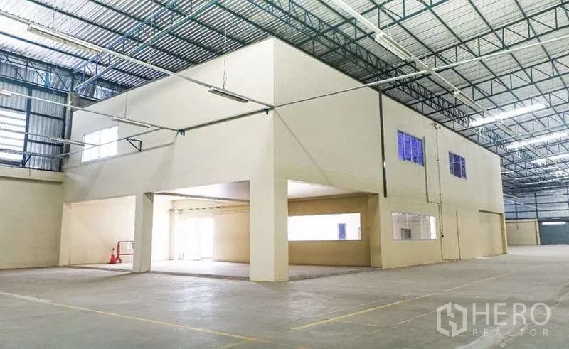 Warehouse for rent in Bang Bo, Samut Prakan - Spacious warehouse interior with a built‑in two‑storey office block and high steel‑truss ceiling.