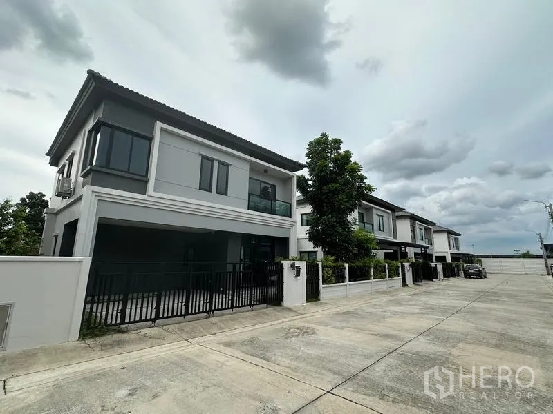 Detached House for sale in Khlong Sam Wa, Bangkok - Quiet neighborhood street with a row of modern detached houses and driveways