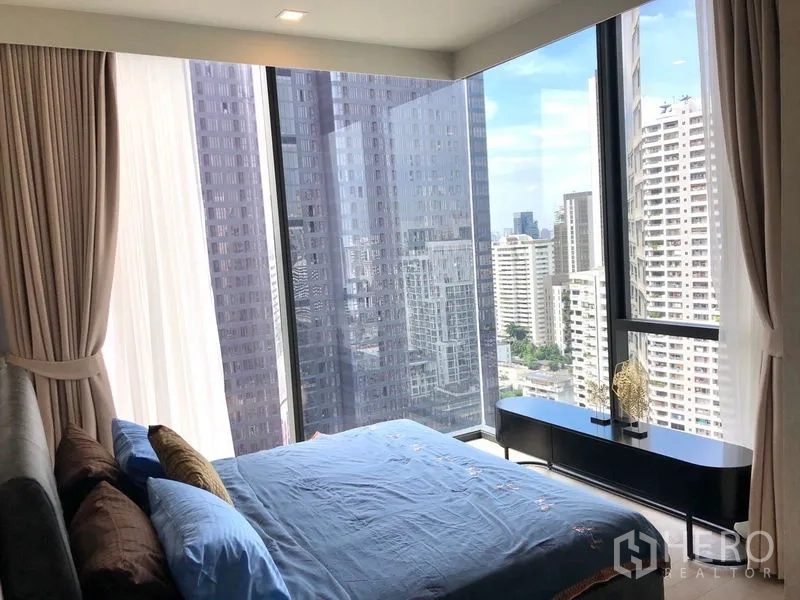 Condominium for rent in Watthana, Bangkok - Master bedroom with corner glass windows showcasing panoramic Bangkok skyline views.