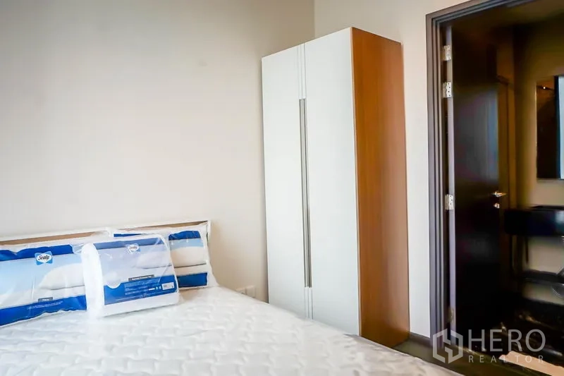 Condominium for sale in Watthana, Bangkok - Bedroom corner featuring a wardrobe and doorway to the bathroom.