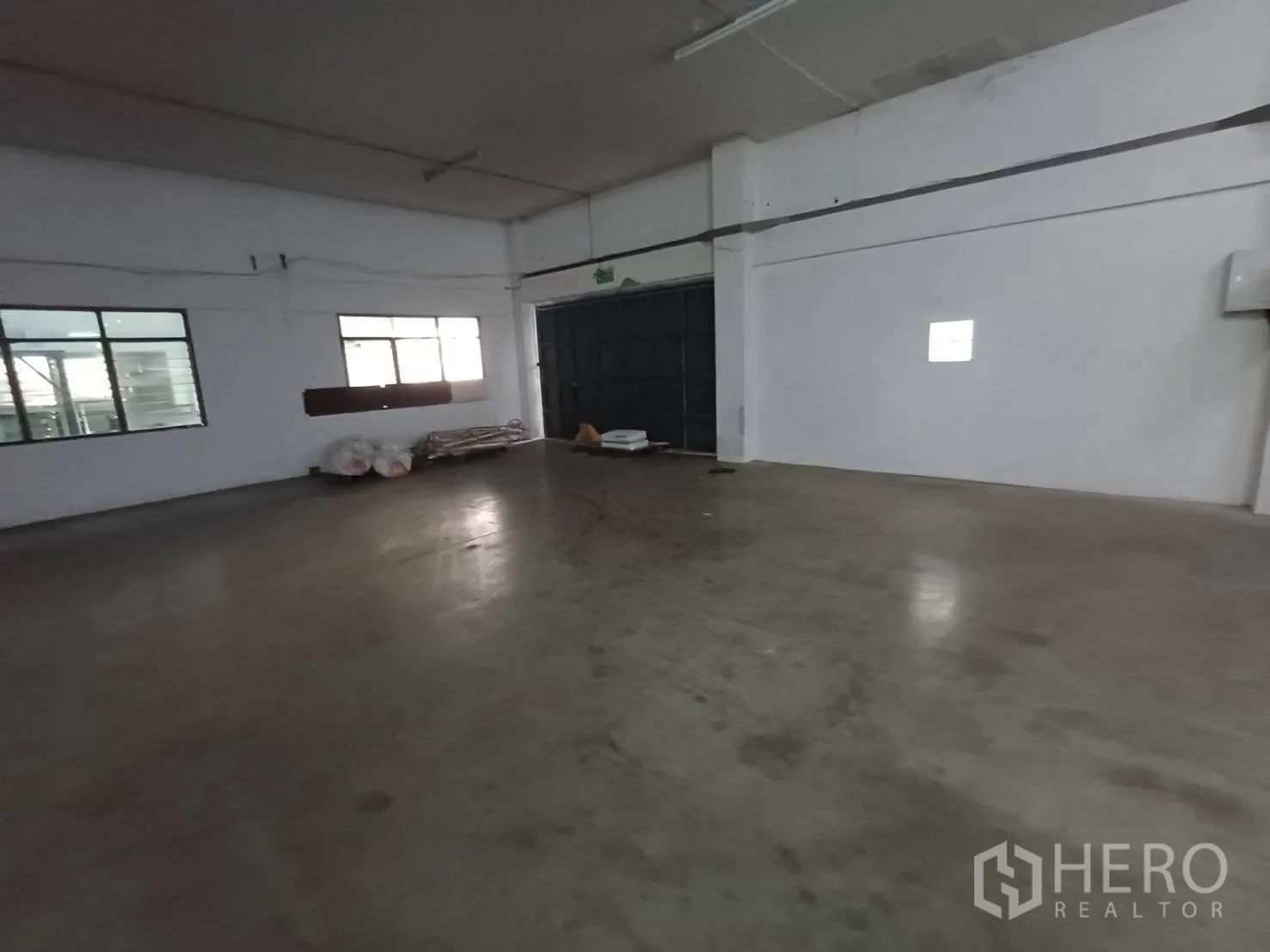 Warehouse for rent in Mueang Samut Prakan, Samut Prakan - Separate room inside the warehouse with windows and a large industrial door.