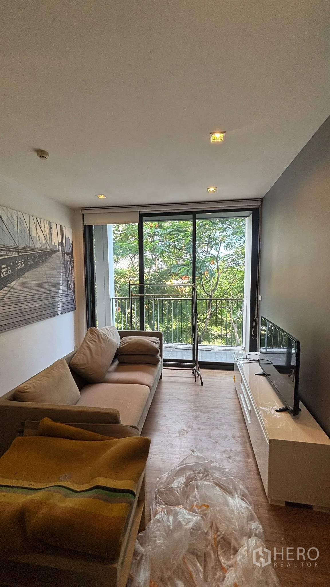 公寓 for rent or sale in Watthana, Bangkok - 客厅配沙发与电视柜，落地滑门通向绿意阳台。
