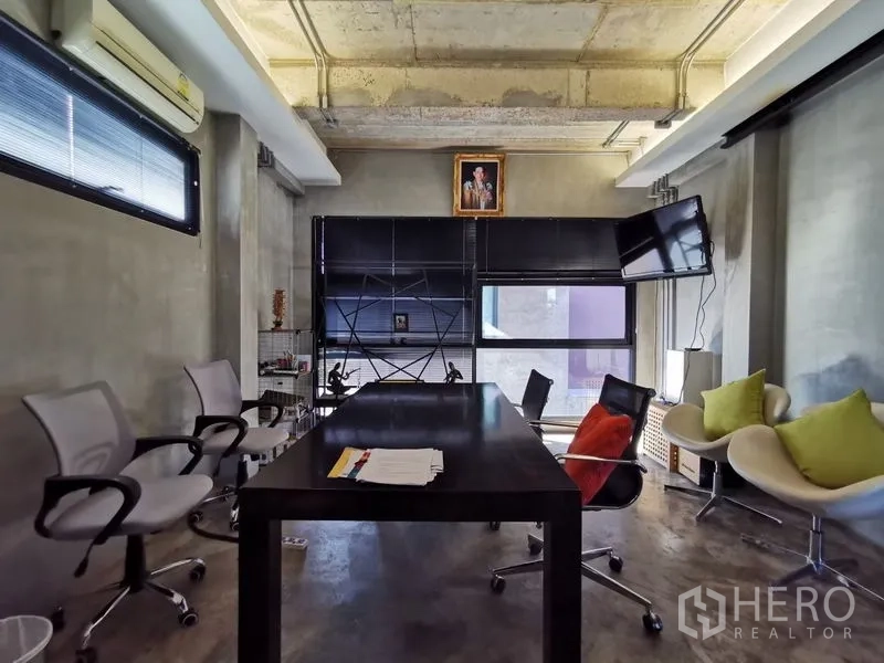 Home Office for sale in Wang Thonglang, Bangkok - Executive office with concrete ceiling, black desk, swivel chairs and a wall-mounted screen.