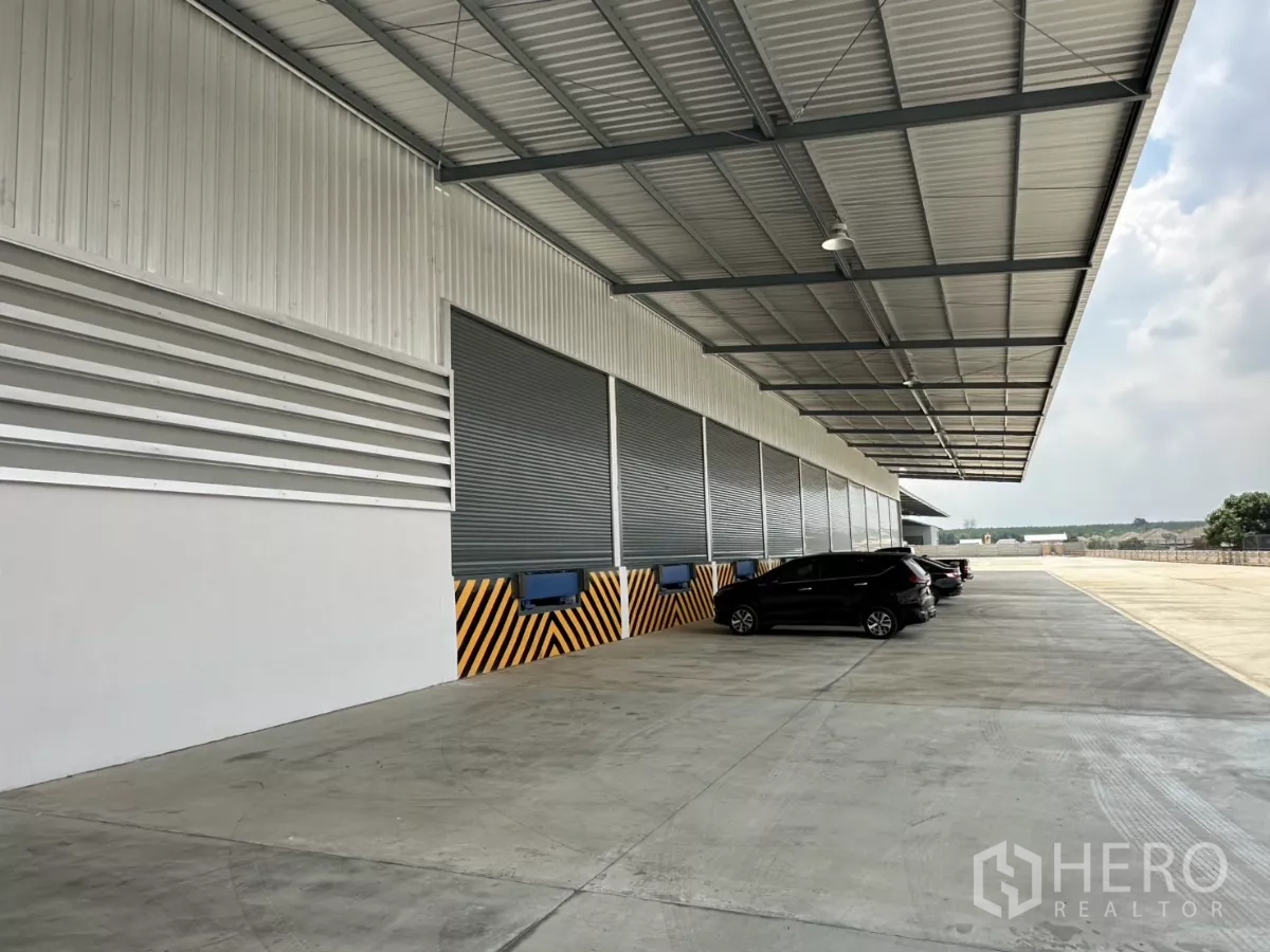Factory for rent in Chon Buri - Covered truck loading bays with roller shutters, dock levelers and parking beside the factory.