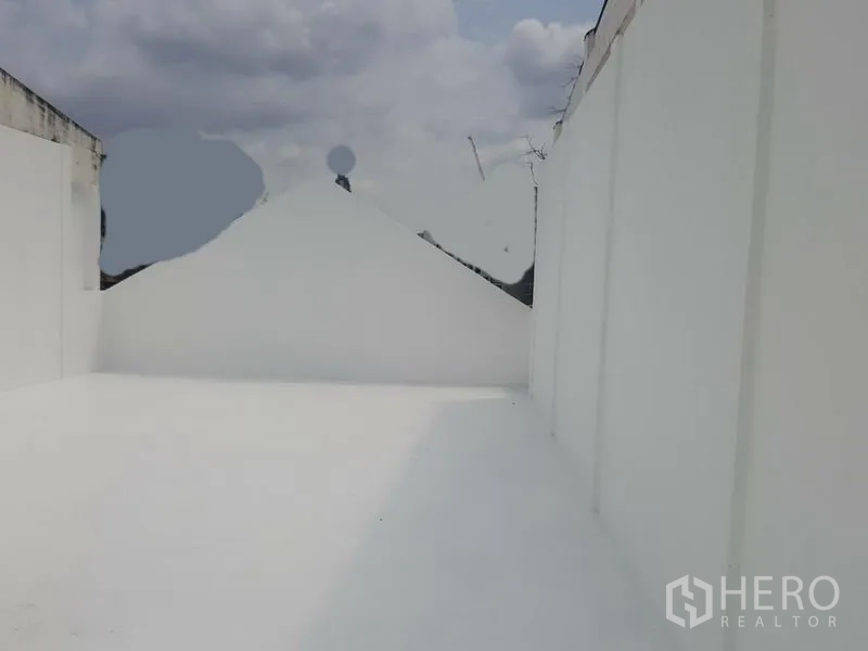 Home Office for rent in Khlong Toei, Bangkok - Rooftop terrace with white walls under a cloudy sky.
