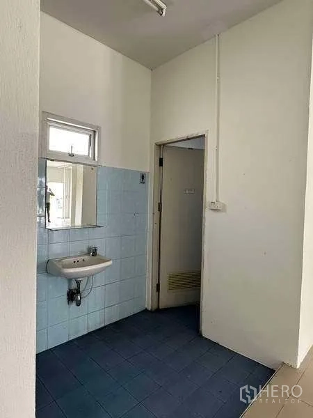 Warehouse for rent in Samut Prakan - Restroom area with sink, mirror and door inside the office block.