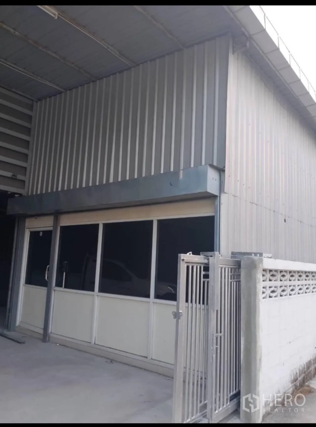 Warehouse for rent in Din Daeng, Bangkok - Warehouse entrance with tall roller shutters and skylit roof panels.