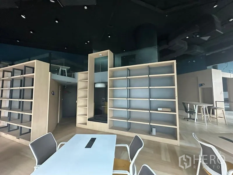 Office Space for rent - Collaborative zone with modern chairs, power-integrated table and multiple built-in shelving units.