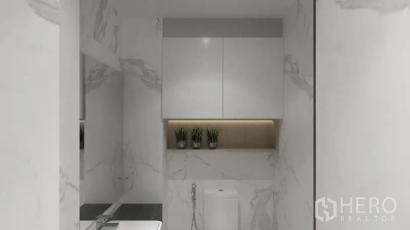 Condominium for rent in Watthana, Bangkok - Guest bathroom with marble walls, concealed shelf and modern toilet.