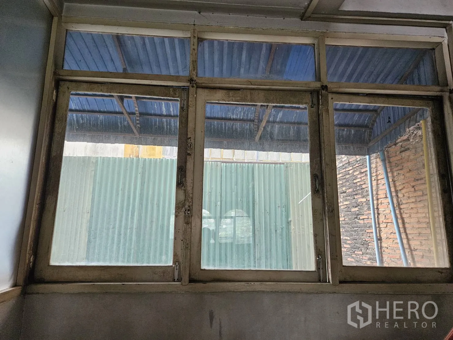 店屋 出租在Watthana, Bangkok - 室内窗户特写，外侧为金属瓦雨棚与砖墙。