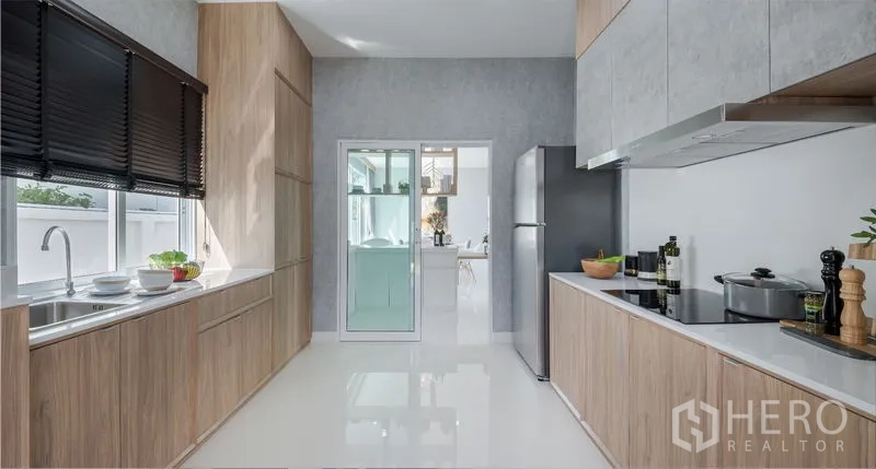 Detached House for sale in Lam Luk Ka, Pathum Thani - Contemporary kitchen with two-tone cabinets, cooktop, refrigerator and sliding glass door.