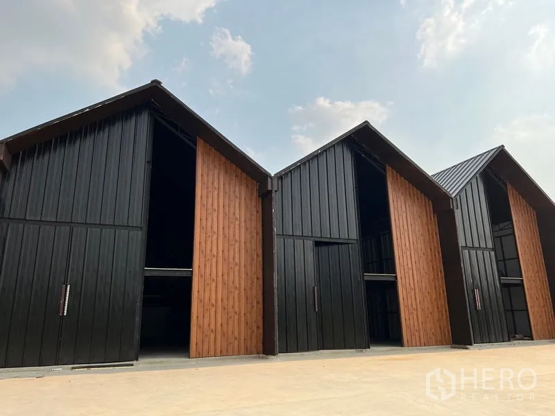 货栈 出租在Bueng Kum, Bangkok - Bueng Kum 现代三角屋顶仓库外观，黑色金属墙板与木质滑门，前方装卸场地宽阔。