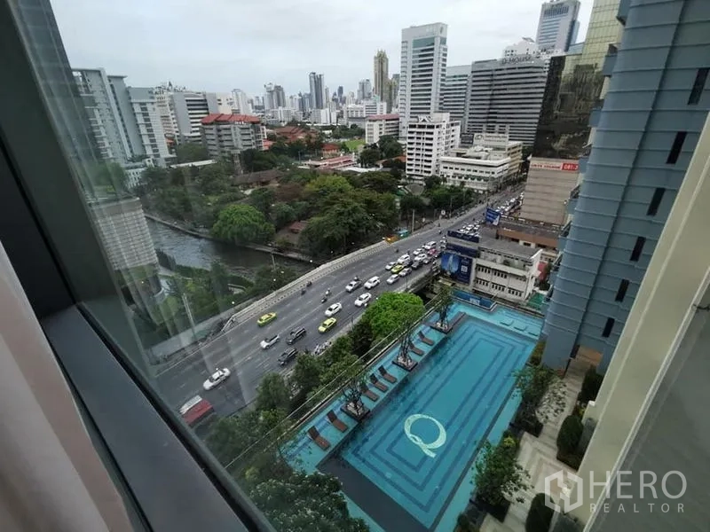 Condominium for rent in Ratchathewi, Bangkok - High-floor view of city skyline, canal, road traffic and large outdoor pool.