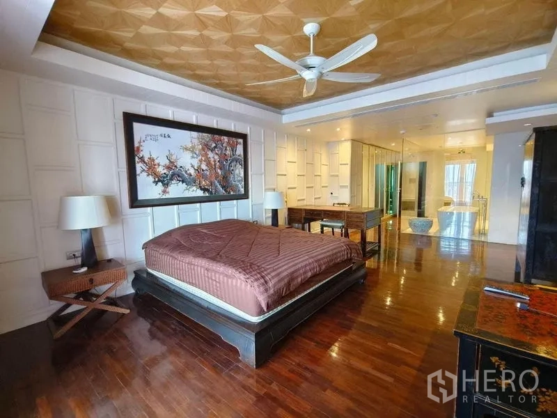 Condominium for rent in Bang Rak, Bangkok - Spacious master bedroom with decorative ceiling, white paneled walls, and glass-partitioned bath.