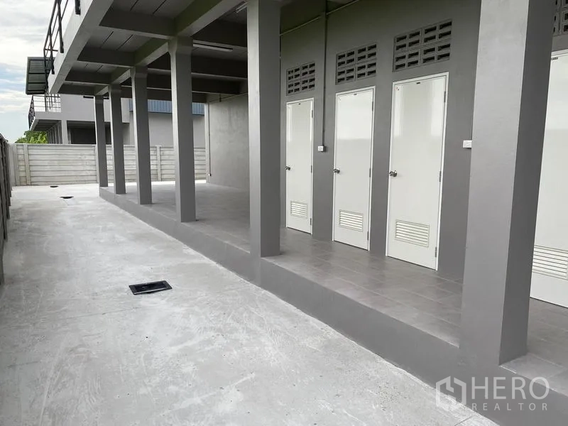 Warehouse for rent or sale in Bang Len, Nakhon Pathom - Covered service corridor with multiple restroom doors at the warehouse.