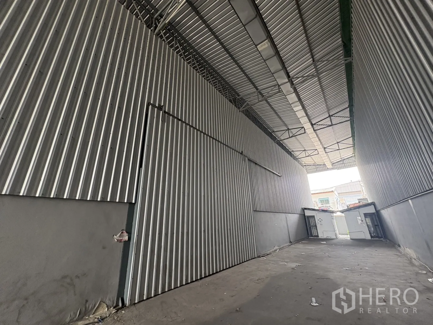 คลังสินค้า ให้เช่าในMueang Samut Prakan, Samut Prakan - ทางสัญจรมีหลังคาคลุมระหว่างอาคารโกดัง ผนังเมทัลชีทสูงและประตูสไลด์.