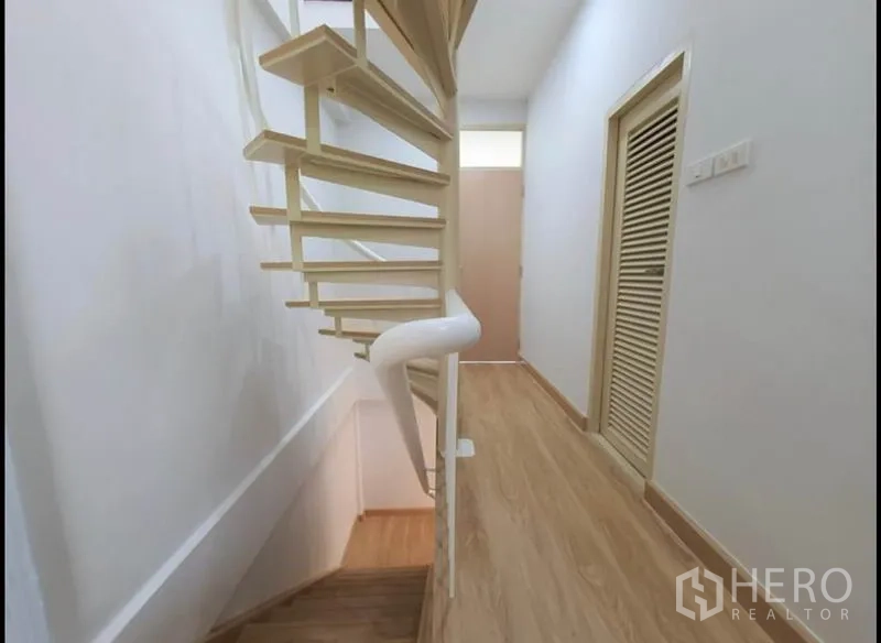 Townhouse for rent in Phaya Thai, Bangkok - Light-toned staircase with white handrail along a clean hallway and storage door.