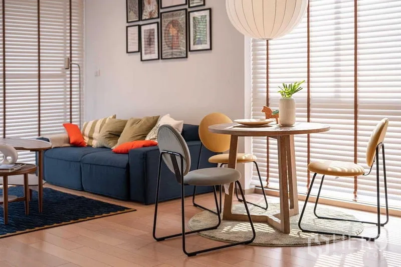 คอนโด ให้เช่าหรือขายในPathum Wan, Bangkok - มุมรับประทานอาหารและโซฟาสีน้ำเงินข้างบานมู่ลี่สูงพร้อมกรอบรูปผนัง